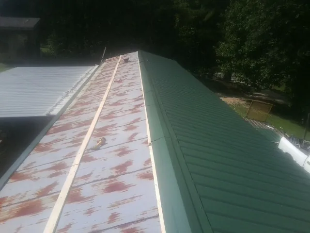 Old rusted panels beside newly installed green metal roofing — Wind Damage Roof Repair by Roofing Brothers in Putnam Station