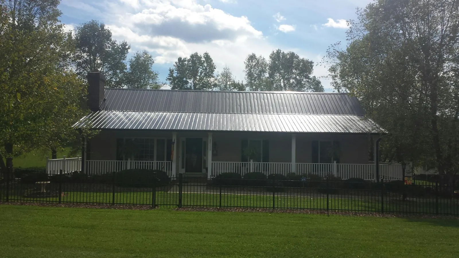 Gray metal roof on a brick ranch with a full width front porch — Gutter Guard Installation work by our crew in Putnam Station