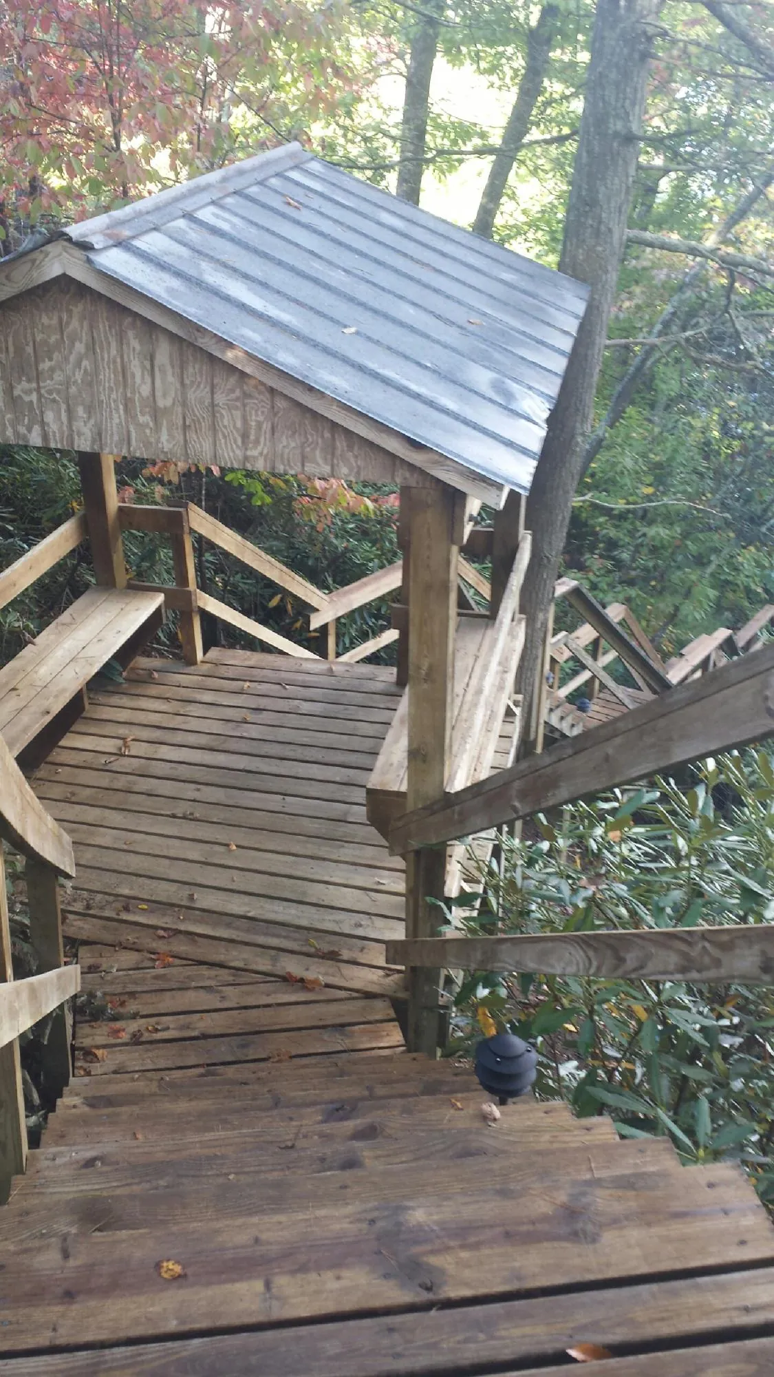 Metal roofed shelter over wooden steps on a wooded walkway — Skylight Repair & Installation work by our crew in Putnam Station