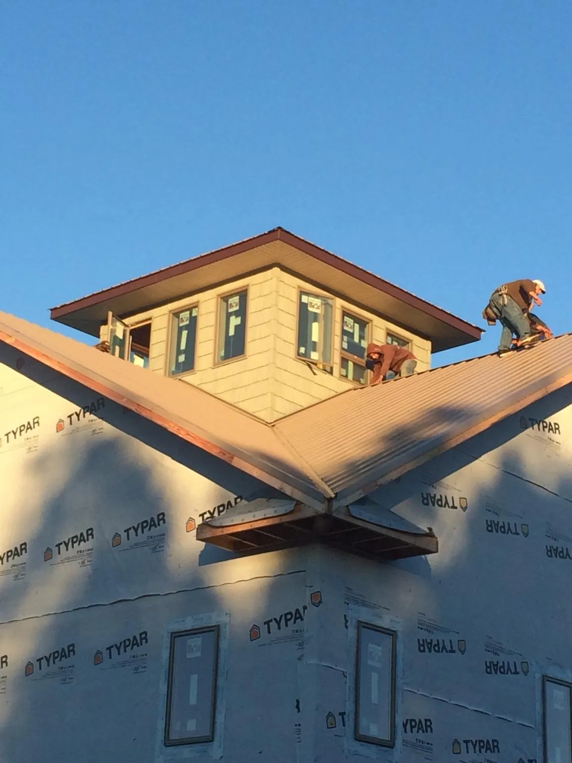 Roofers working around a rooftop cupola on a new metal roof at sunset — Roof Waterproofing in Putnam Station by Roofing Brothers
